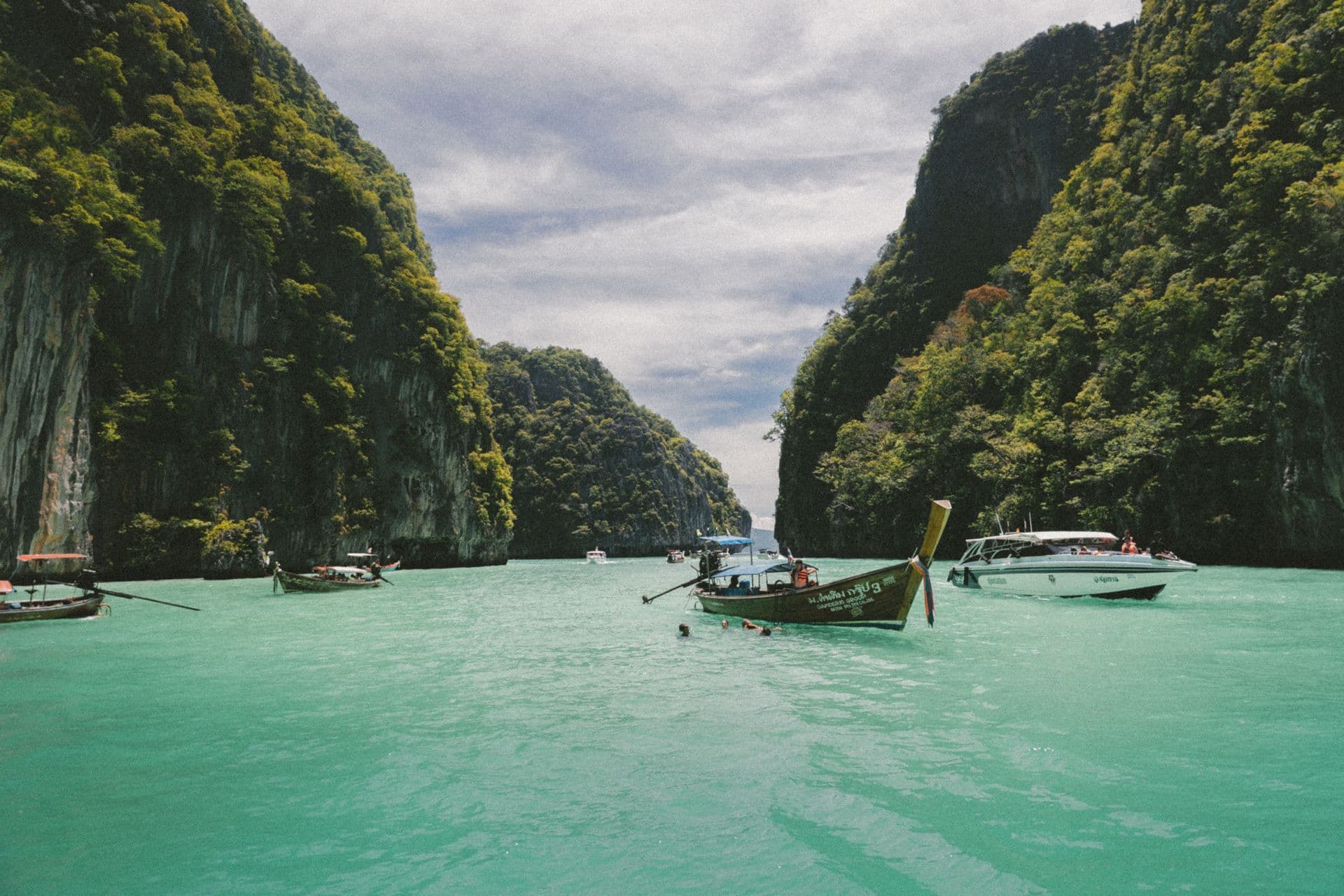 Long-tail boats between limestone cliffs